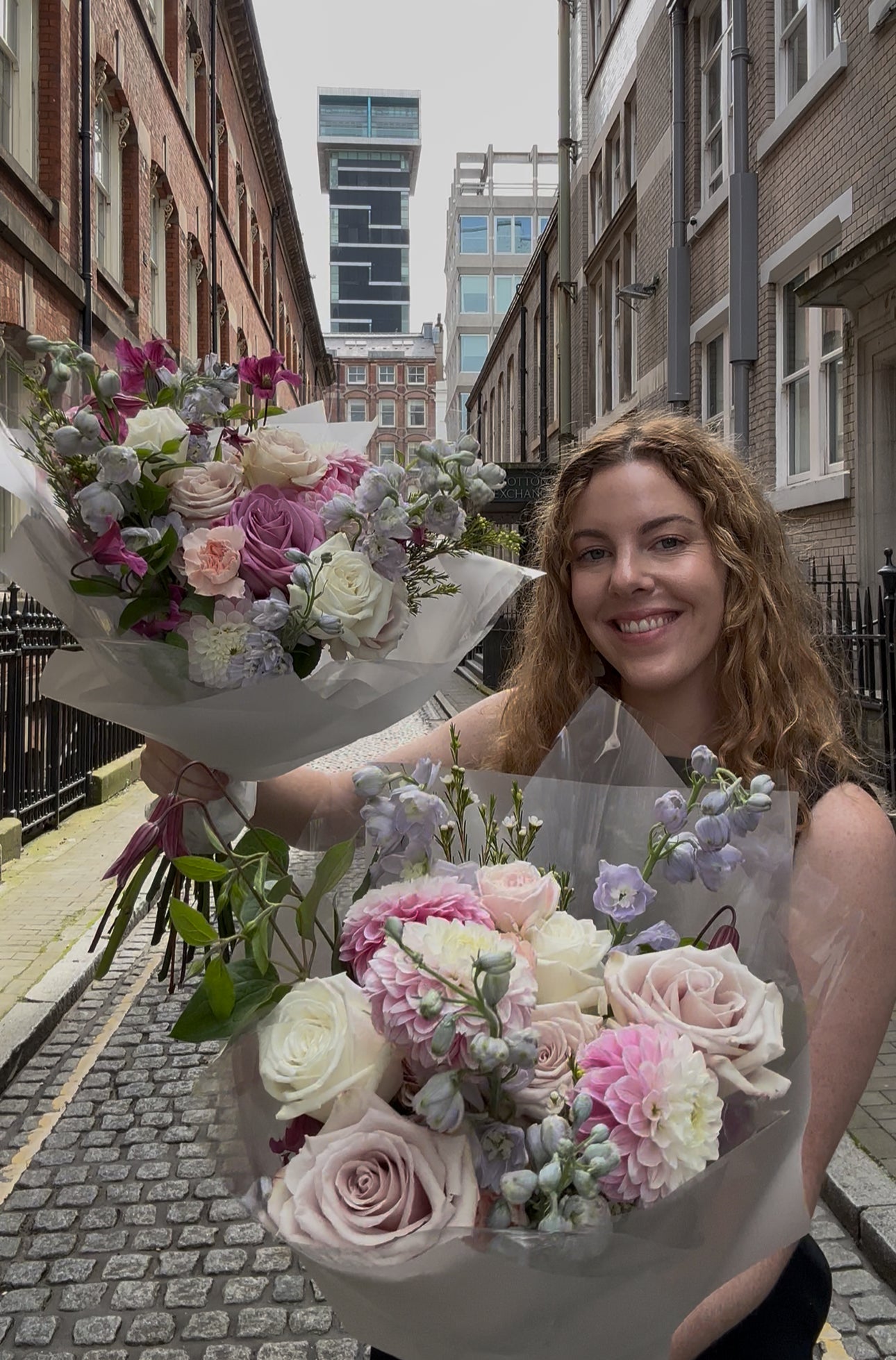 Woman holding two bouquets of flowers in an urban setting